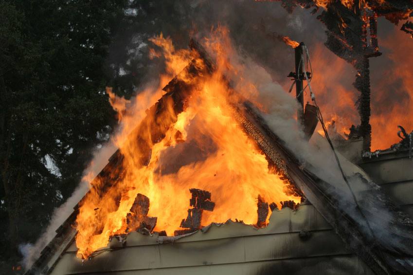 A close up of fire burning out of control in the gable of a house.